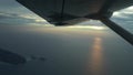 Airplane wing view from jetplane window on the sky in twilight sunset behind cloud at horizontal line and reflex golden orange lig