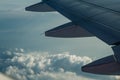 An airplane wing through airplane window with a cloudy sky Royalty Free Stock Photo