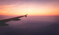 Airplane wings in the sky and a mountains view scene in the sunrise. Travel and adventure.