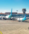 Airplanes and truck at runway in morning sunlight, Denpasar airport building, Bali, Indonesia