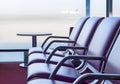 Bench in departure flights waiting hall at the airport with airplane in the background