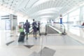 Airport blurred background interior with people travelers and air hostess with luggage on passage escalator walkway in