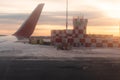 Airport building at dawn on the runway with flashing beacon painted in red and white checkerboard squares. airplane window view