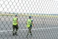 Airport employees are on the runway. The territory of the private airfield is fenced with barbed wire and a fence. The traffic