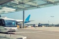 Airport environment and services. Shuttle bus waiting for passengers at terminal building. Big commercial plane on airfield. Royalty Free Stock Photo