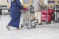 Airport luggage Trolley with suitcases, unidentified man woman walking in the airport, station, France Royalty Free Stock Photo