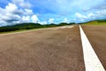Airport Runway Taxi with white line, green mountain and blue sky