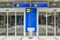 Airport terminal building gate entrance and automatic glass door with info text in german and english. Modern airport glass wall