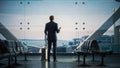 Airport Terminal: Businessman with Rolling Suitcase Walks, Uses Smartphone App for e-Business. Bac Royalty Free Stock Photo