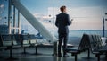 Airport Terminal: Businessman with Rolling Suitcase Walks, Uses Smartphone App for e-Business. Bac Royalty Free Stock Photo