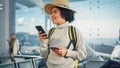 Airport Terminal: Happy Traveling Black Woman Waiting at Flight Gates for Plane Boarding, Uses Mob Royalty Free Stock Photo