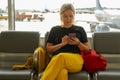 Airport terminal. Woman waiting for flight using smartphone. Girl with cell phone in airport surfing internet social Royalty Free Stock Photo