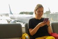 Airport terminal. Woman waiting for flight using smartphone. Girl with cell phone in airport surfing internet social Royalty Free Stock Photo