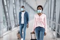 Airport Travel Precautions. Man And Woman Wearing Medical Masks Walking At Terminal