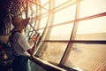 Airport, woman is waiting for plane in terminal on background windows, writes messages to friends and relatives in Royalty Free Stock Photo