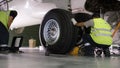 Airport worker checking chassis. Engine and chassis of the passenger airplane under heavy maintenance. Engineer checks Royalty Free Stock Photo