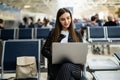 Airport Young female passenger with laptop sitting in terminal hall while waiting for her flight. Air travel concept with young Royalty Free Stock Photo