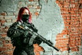 Airsoft soldier red-hair woman in uniform with machine gun inside broken building