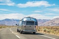 Airstream Camper on two laned highway driving through sagebrush toward mountain range with electrical Royalty Free Stock Photo