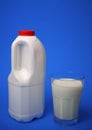 Airtight one gallon milk jug with a red cap and full glass milk.