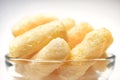 Airy Crisps, Corn Puffs, Puffcorn Snacks in a Glass Bowl on Clear Background. Crunchy Flavored Puffed Ready to Eat Treats. Party, Royalty Free Stock Photo