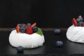 Airy meringue with fresh berries on black background. Cake Anna Pavlova. Close up