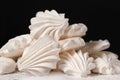 Airy sweet meringue on powdered sugar on a black background close-up, side view.