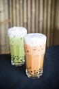 Asian style green and orange bubble tea with milk froth on top