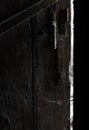 Fragment of an old open wooden door in a dark room. Royalty Free Stock Photo