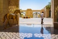 Ajman. August 2016. The clerk and the sculpture golden horse in front of the hotel Ajman Saray.