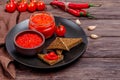 Ajvar or pindjur red vegetable spread or pepper paprika and tomato mousse in a clay bowl and glass jar in a black plate on a Royalty Free Stock Photo