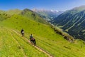 AK SU, KYRGYZSTAN - JULY 19, 2018: Horse riding tourist with a guide near Ak Su valley near Karakol, Kyrgyzst