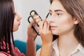 Akeup artist applies makeup to attractive brunette girl at the m