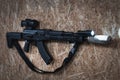 AKM tactical rifle with a silencer, a weapon flashlight and a prismatic sight hangs on the wall in a shooting range Royalty Free Stock Photo