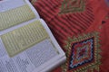 Al Quran di sajadah dengan latar belakang putih.
