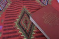 Al Quran di sajadah dengan latar belakang putih.