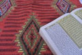 Al Quran di sajadah dengan latar belakang putih.