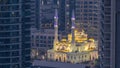 Al Raheem mosque between skyscrapers day to night on the marina walk in Dubai Marina, Dubai, UAE. Royalty Free Stock Photo