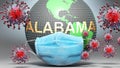 Alabama and covid - Earth globe protected with a blue mask against attacking corona viruses to show the relation between Alabama