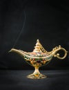 Aladdin magic lamp on black with smoke .A gold genie lamp with smoke on black background Royalty Free Stock Photo