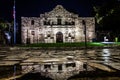 The Alamo in San Antonio, Texas during night after a rainfall with the building reflecting in water puddles