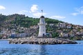 Alanya lighthouse on the background of a hill with modern cottages and the old town on a summer sunny day. Panorama of the Turkish