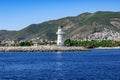 Alanya lighthouse with the Turkish flag on the roof against the background of a mountain panorama of the Mediterranean coast.