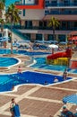 A group of plump women sitting on the edge of the pool and talking. Women are dressed in bathing suits. Tourists have a rest at