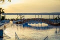 View of the pool and the sea at sunset. Near the pool are sun loungers, palm trees grow. The Royalty Free Stock Photo