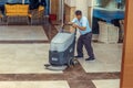 A worker using a machine polishes and cleans the floor in the lobby of a business center or a Royalty Free Stock Photo