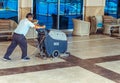 A worker using a machine polishes and cleans the floor in the lobby of a business center or a Royalty Free Stock Photo