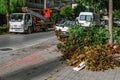 A pile of cut branches with dry leaves on the background of an autotower on a city street in