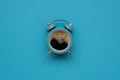 Alarm clock as coffee cup on blue background. Top view. Flat lay. Good morning concept Royalty Free Stock Photo