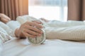 alarm clock and asian woman hand stop time in bed while sleeping, young adult female wake up late in the early morning. Relaxing Royalty Free Stock Photo